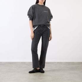 Model wearing Anine Bing black cotton sweat top with short sleeves, styled with dark wash straight-leg jeans and black trainers.