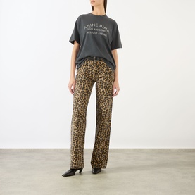 Model wearing Anine Bing washed black graphic logo T-shirt, styled with leopard print flared trousers and black heeled mules.