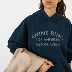 Model wearing Anine Bing navy cotton hoodie with Los Angeles Melrose Avenue logo print, styled with a beige coat
