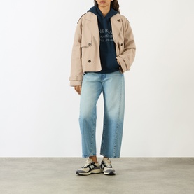 Model wearing Anine Bing navy cotton sweat top with beige cropped jacket, light wash straight-leg jeans and chunky trainers.