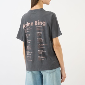 Model wearing Anine Bing washed grey T-shirt, back view showing pink logo and city tour print, styled with light blue denim jeans.
