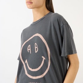Model wearing Anine Bing washed grey T-shirt with oversized pink smiley face AB logo graphic print, relaxed fit, crew neck.