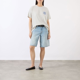 Model wearing Anine Bing Cade Wave Logo T-Shirt in Heather Grey, styled with light-wash denim shorts and black ballet flats.