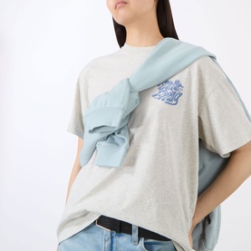 Model wearing Anine Bing Cade Wave Logo T-Shirt in Heather Grey with blue logo detail, styled with a light blue shirt tied over shoulders.