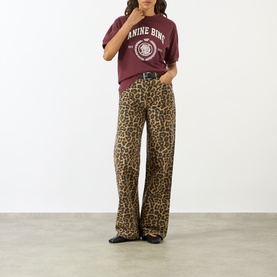 Model wearing Anine Bing burgundy cotton logo T-shirt, styled with leopard print wide-leg jeans and black loafers.