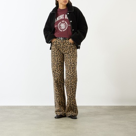 Model wearing Anine Bing burgundy graphic cotton T-shirt, styled with black jacket and leopard print wide-leg trousers.
