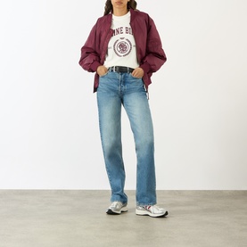 Model wearing Anine Bing ecru graphic cotton T-shirt, styled with burgundy jacket, light blue straight-leg jeans and silver trainers.
