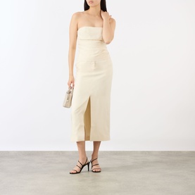 Model wearing Anine Bing cream strapless bandeau top, styled with a matching midi skirt, small clutch bag and black strappy heels.