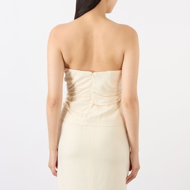 Model wearing Anine Bing cream strapless top, back view, with ruched detail and boning, paired with matching cream skirt.