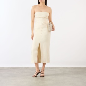 Model wearing Anine Bing cream strapless bandeau top, styled with a matching midi skirt, small clutch bag, and black strappy sandals.