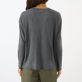 Model wearing Anine Bing Ivan Paris Stencil Top in black, long sleeves, dropped shoulders, straight hem, back view. Styled with khaki trousers.