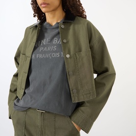 Model wearing Anine Bing Ivan Paris Stencil Top in black, styled with an olive green cropped jacket and matching trousers.