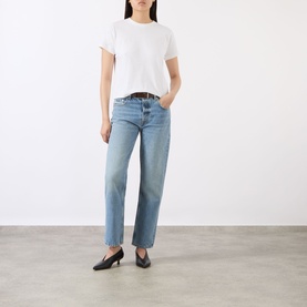 Model wearing Anine Bing white cotton T-shirt, styled with light blue straight-leg jeans, brown belt and black heeled mules.