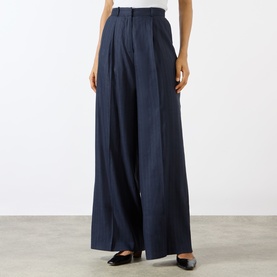 Model wearing Anine Bing Paola Tonal Striped Trousers in Navy Pinstripe; high-rise, wide-leg with front pleats, styled with black mules.