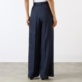 Model wearing Anine Bing Paola Tonal Striped Trousers in Navy Pinstripe, high-rise wide-leg silhouette with front pleats and pressed creases, rear