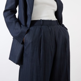 Model wearing Anine Bing Paola Tonal Striped Trousers in navy pinstripe, high-rise wide-leg with front pleats, styled with matching blazer and white