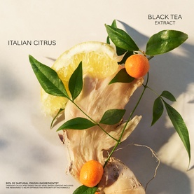 Bulgari Black Tea Extract Italian Citrus EDT lifestyle shot with lemon slice, kumquats and green botanical leaves on neutral background.