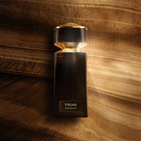 Bulgari Tygar Extrait de Parfum in a black and gold bottle, shown flat lay on warm wood-toned surface