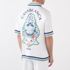 Model wearing Casablanca Hotel Emblem Silk Shirt in white with multicolour back graphic, green and blue stripe trims, short sleeves.