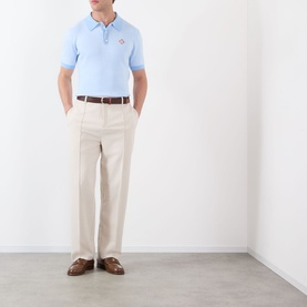 Model wearing Casablanca Pinstripe Logo Polo Shirt in light blue with cream trousers and brown leather loafers.