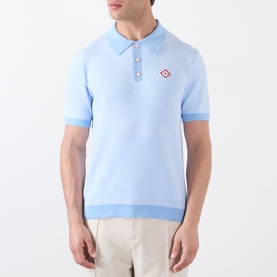 Model wearing Casablanca Pinstripe Logo Polo Shirt in light blue, short sleeves, ribbed trims, diamond logo at chest, styled with cream trousers