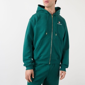 Model wearing Casablanca Sport hoodie in green, zip-through style with gold zip, drawstring hood and small chest logo, styled with matching green