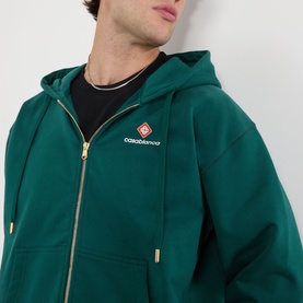 Model wearing Casablanca Sport Type hoodie in green with gold zip, logo patch on chest, styled over black crew neck top