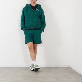 Model wearing Casablanca Sport green zip-up hoodie with matching shorts, styled with white trainers and black top underneath.