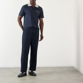 Model wearing Casablanca Laurel Piqu&eacute; Polo Shirt in navy with laurel-embroidered collar, styled with matching navy trousers and black loafers.