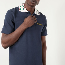 Model wearing Casablanca Laurel Piqu&eacute; Polo Shirt in navy with embroidered laurel collar detail and yellow logo at chest