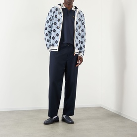 Model wearing Casablanca Laurel Piqu&eacute; Polo Shirt in navy, styled with a monogram zip hoodie and wide-leg trousers.