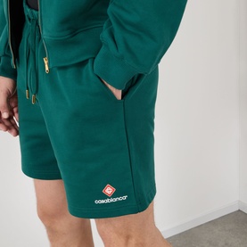 Model wearing Casablanca Logo Sweat Shorts in green with embroidered logo, styled with matching green zip-up hoodie with gold hardware.