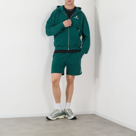 Model wearing Casablanca Logo Sweat Shorts in green with matching zip-up hoodie and white trainers.