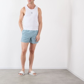Model wearing Casablanca Monogram Motif Swim Shorts in Cubist CC Monogram print, styled with white vest and white slides.