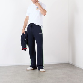 Model wearing Casablanca Classic Logo Graphic T-Shirt in white, styled with navy side-stripe trousers and white shoes.