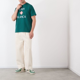 Model wearing Casablanca Diamond Logo T-Shirt in green with stacked logo print, styled with cream wide-leg trousers and green trainers.