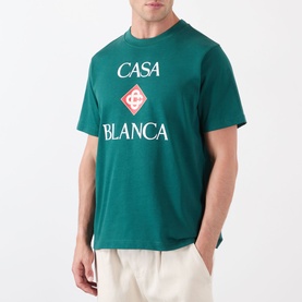 Model wearing Casablanca Diamond Logo T-Shirt in green with stacked Casa Blanca diamond graphic print, styled with cream trousers.