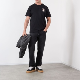 Model wearing Casablanca Casa Way Logo Graphic T-Shirt in black with dark jeans, carrying a grey jacket, styled with cream and black trainers.