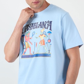 Model wearing Casablanca Egyptian Tennis Match Logo T-Shirt in light blue with Egyptian-style tennis graphic print at chest, crew neckline visible