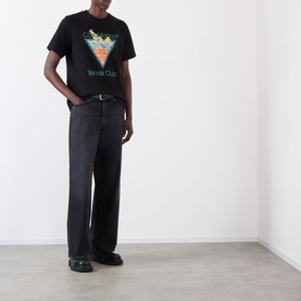 Model wearing Casablanca Tennis Club Icon Pyramid Abduction T-Shirt in black with graphic print, styled with wide-leg dark jeans and black loafers.