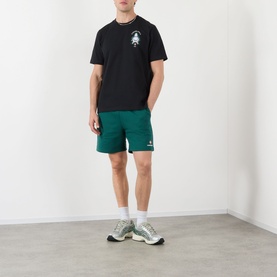 Model wearing Casablanca Hotel Emblem black cotton T-shirt, styled with green shorts and grey trainers