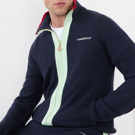 Model wearing Casablanca Logo Merino Wool Track Jacket in navy with mint green contrast stripe, red collar trim, and gold logo zip puller.