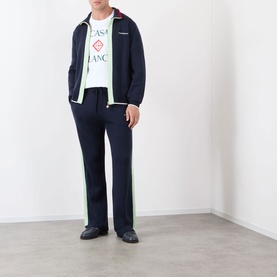 Model wearing Casablanca Logo Merino Wool Track Jacket in navy with green contrast stripes, paired with matching track trousers and white logo tee.