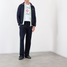 Model wearing Casablanca Logo Merino Wool Track Pants in navy with green side stripe, paired with matching track jacket and white logo tee.