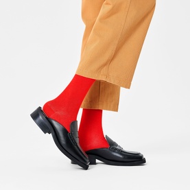 Model wearing Happy Socks in red, styled with camel wide-leg trousers and black leather penny loafers.