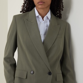 Model wearing Hugo Boss blazer in khaki green, double-breasted with peak lapels, styled with a white shirt underneath.