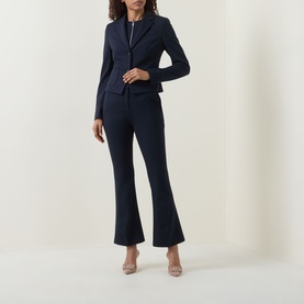 Model wearing navy tailored blazer and matching flared trousers, styled with nude heels