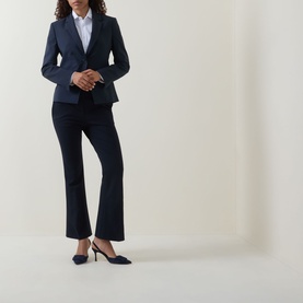 Model wearing Hugo Boss dark blue virgin wool blazer with matching flared trousers, white shirt, and navy kitten heel mules.