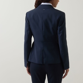 Model wearing Hugo Boss dark blue virgin wool blazer, rear view, styled with matching trousers and white collared shirt.