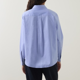 Model wearing Hugo Boss light pastel purple cotton blouse, rear view showing relaxed fit with back pleat detail and long sleeves.